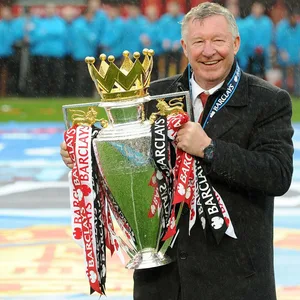 Sir Alex Ferguson hält lachend einen Pokal in der Hand