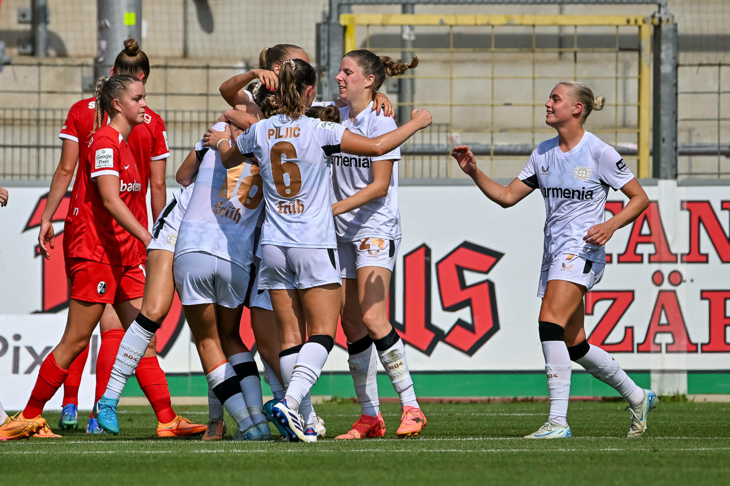 Frauenmannschaft von Bayer Leverkusen steht in einer Jubeltraube beim Spiel gegen den SC Freiburg