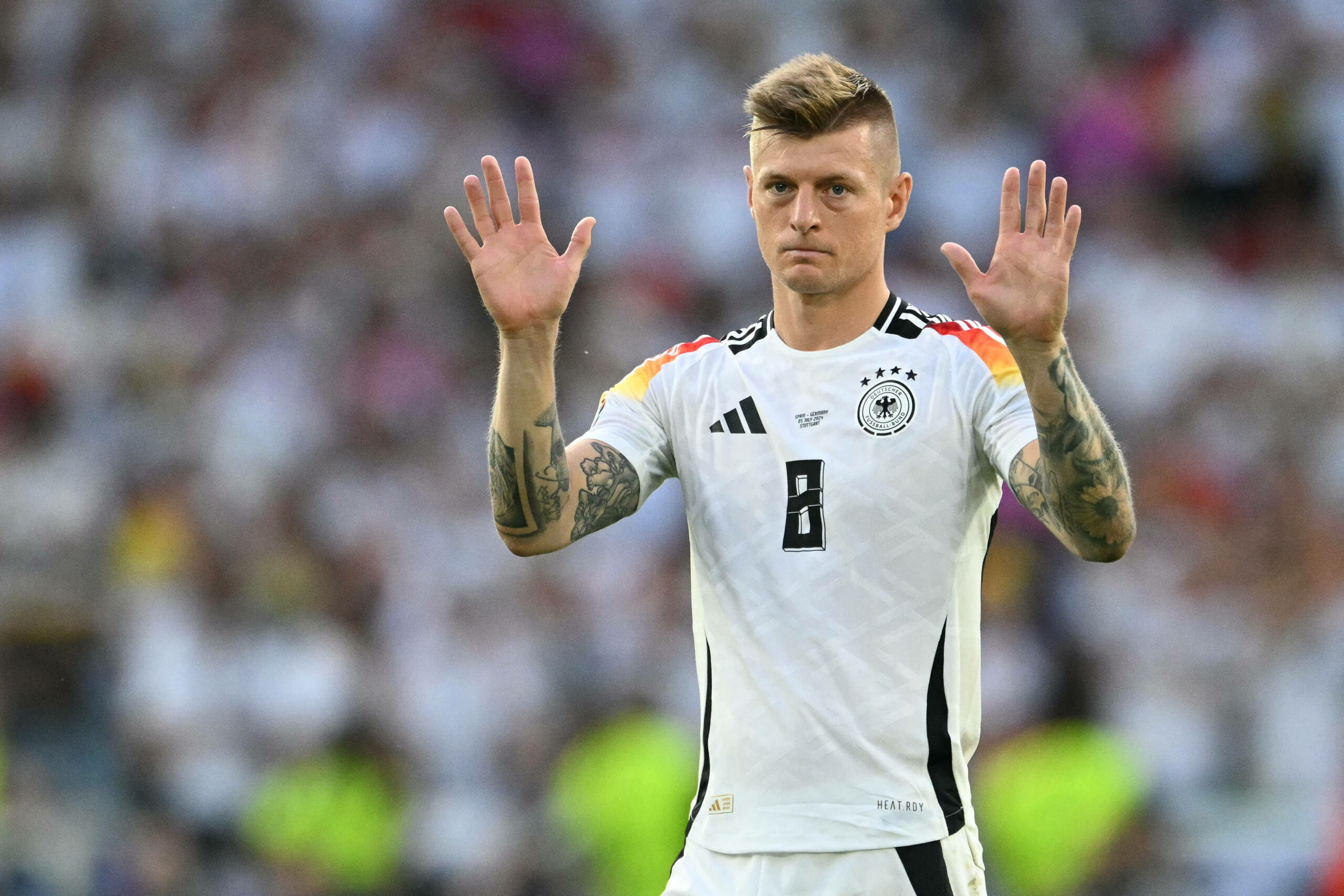 Toni Kroos hebt beide Hände in die Luft.