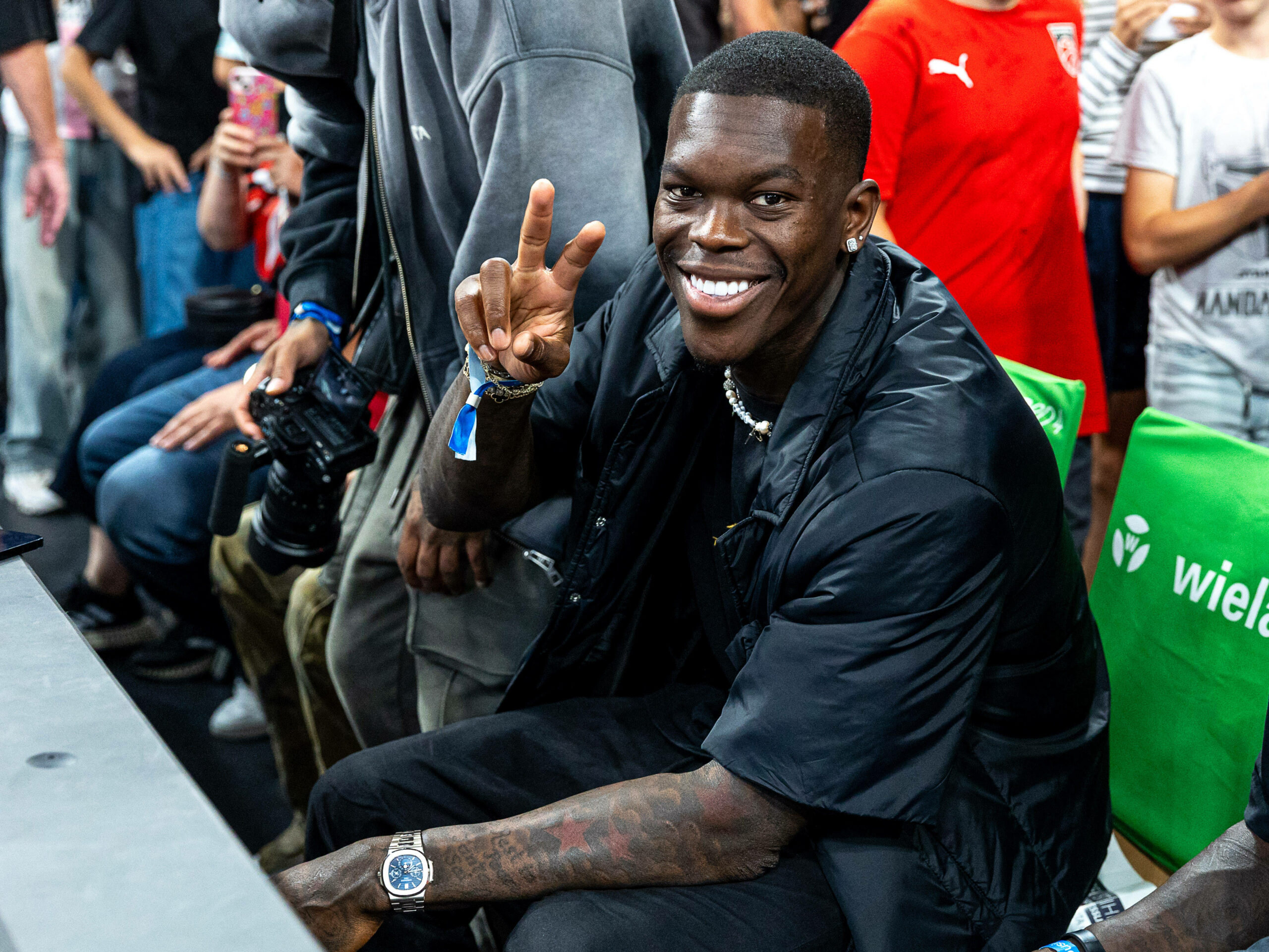 Dennis Schröder lächelt und zeigt das Peace-Zeichen in die Kamera