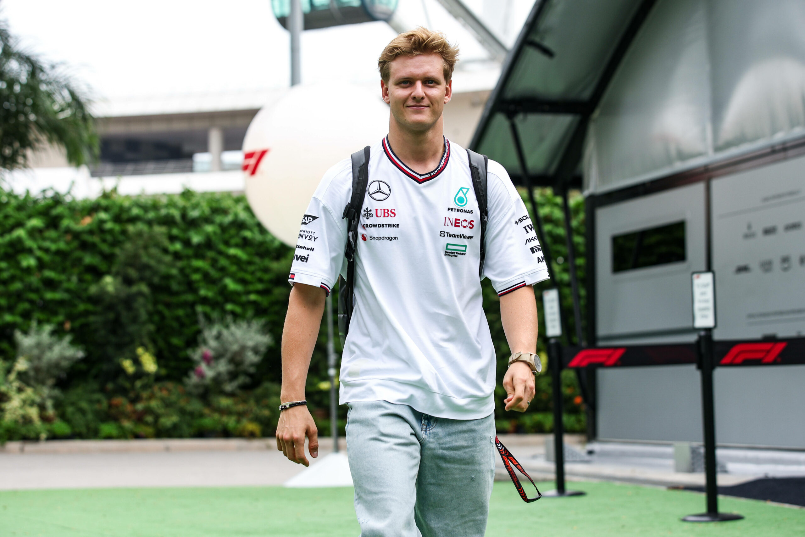 Mick Schumacher geht in Mercedes-Shirt lächelnd auf die Kamera zu