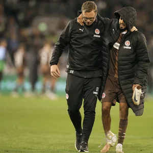 Elias Saad (FC St. Pauli) wird von einem Betreuer gestützt, während er vom Platz geht