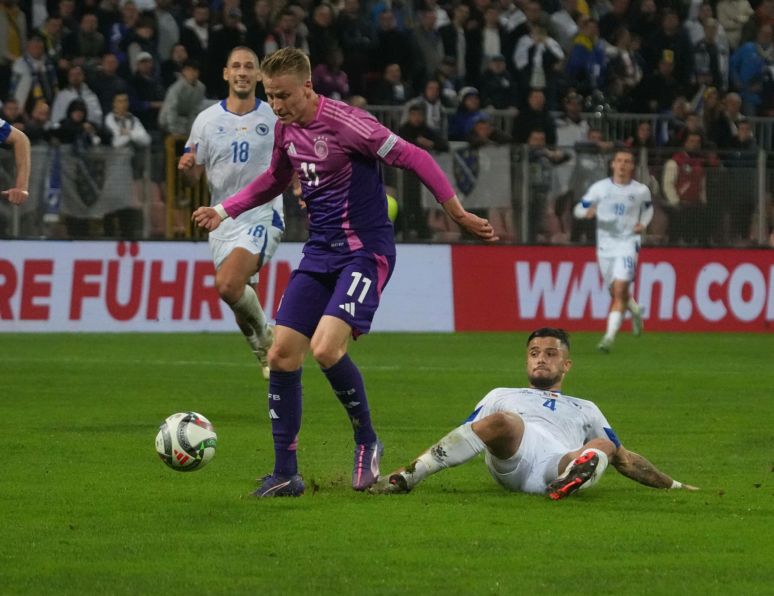 Jusuf Gazibegovic (Bosnien Herzegowina) grätscht Chris Führich (Deutschland), der den Ball führt