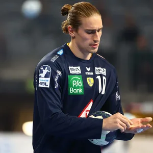 Juri Knorr (Rhein-Neckar Löwen) guckt im Spiel gegen den HSV Hamburg zu seinem verletzten Finger