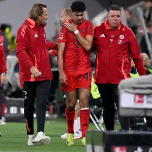 Aleksandar Pavlovic wird verletzt von Bayern-München-Betreuern vom Platz begleitet