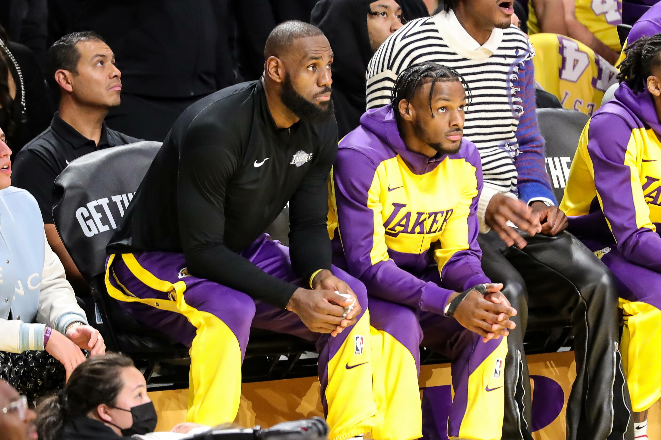 LeBron James und Bronny James sitzen nebeneinander und schauen auf das Spielfeld