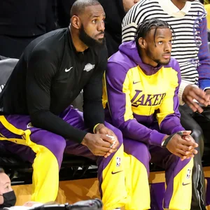 LeBron James und Bronny James sitzen nebeneinander und schauen auf das Spielfeld