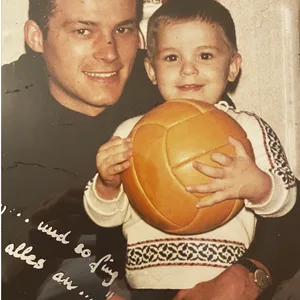 Stefan Kuntz als Kleinkind mit einem Ball in der Hand im Arm seines Vaters