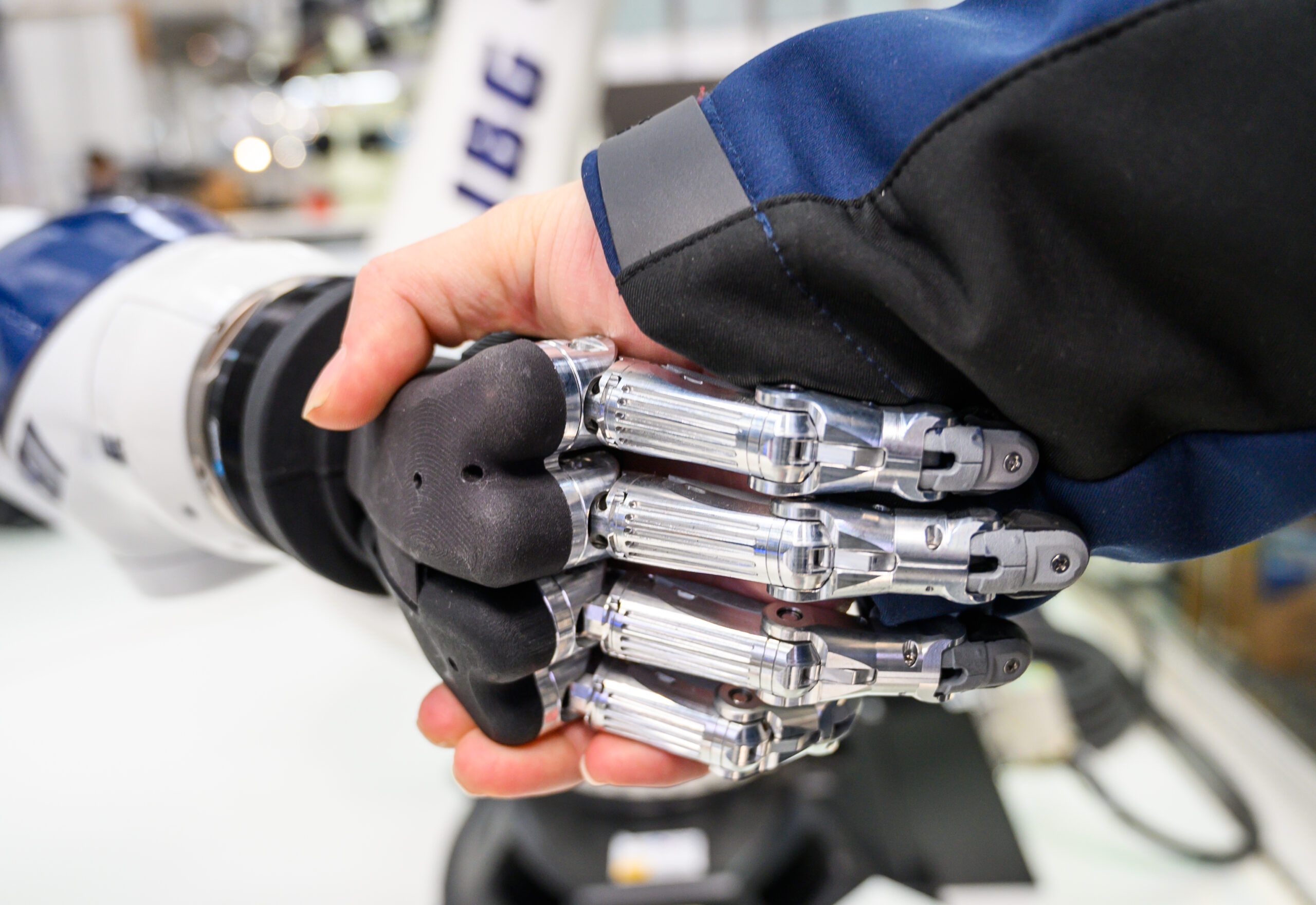 An einem Stand auf der Hannover Messe gibt ein Mann einem Roboter die Hand.