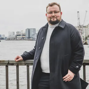 Mann in Mantel vor Hafenkulisse