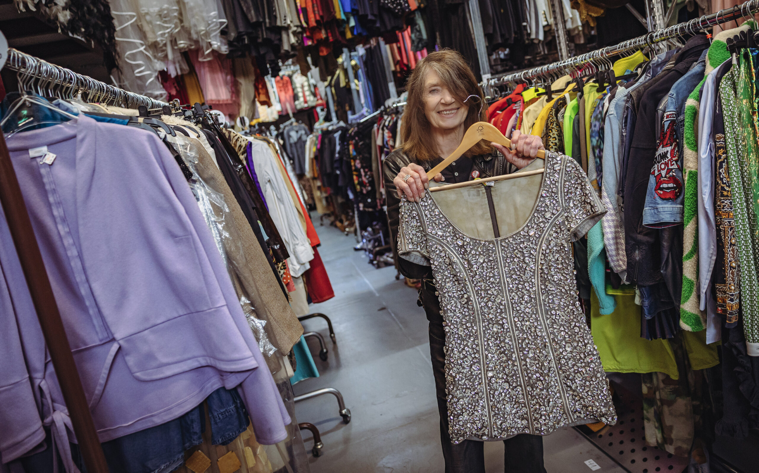 Bigo hält ein kurzes silbernes Glitzerkleid in die Höhe