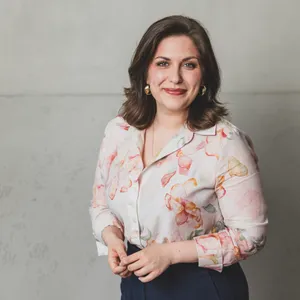 Junge brünette Frau in heller Bluse, lächelnd