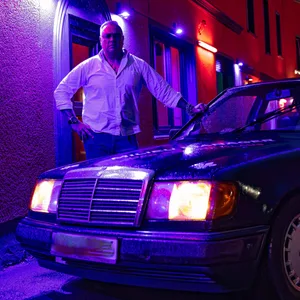 Mann steht an einem alten Mercedes in Abendstimmung