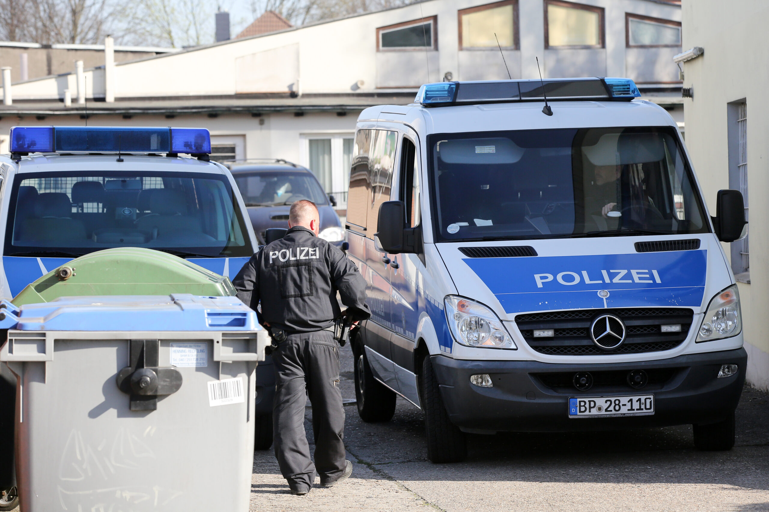 Polizisten stehen während einer Durchsuchung vor einem Haus