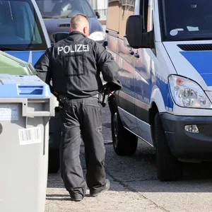 Polizisten stehen während einer Durchsuchung vor einem Haus