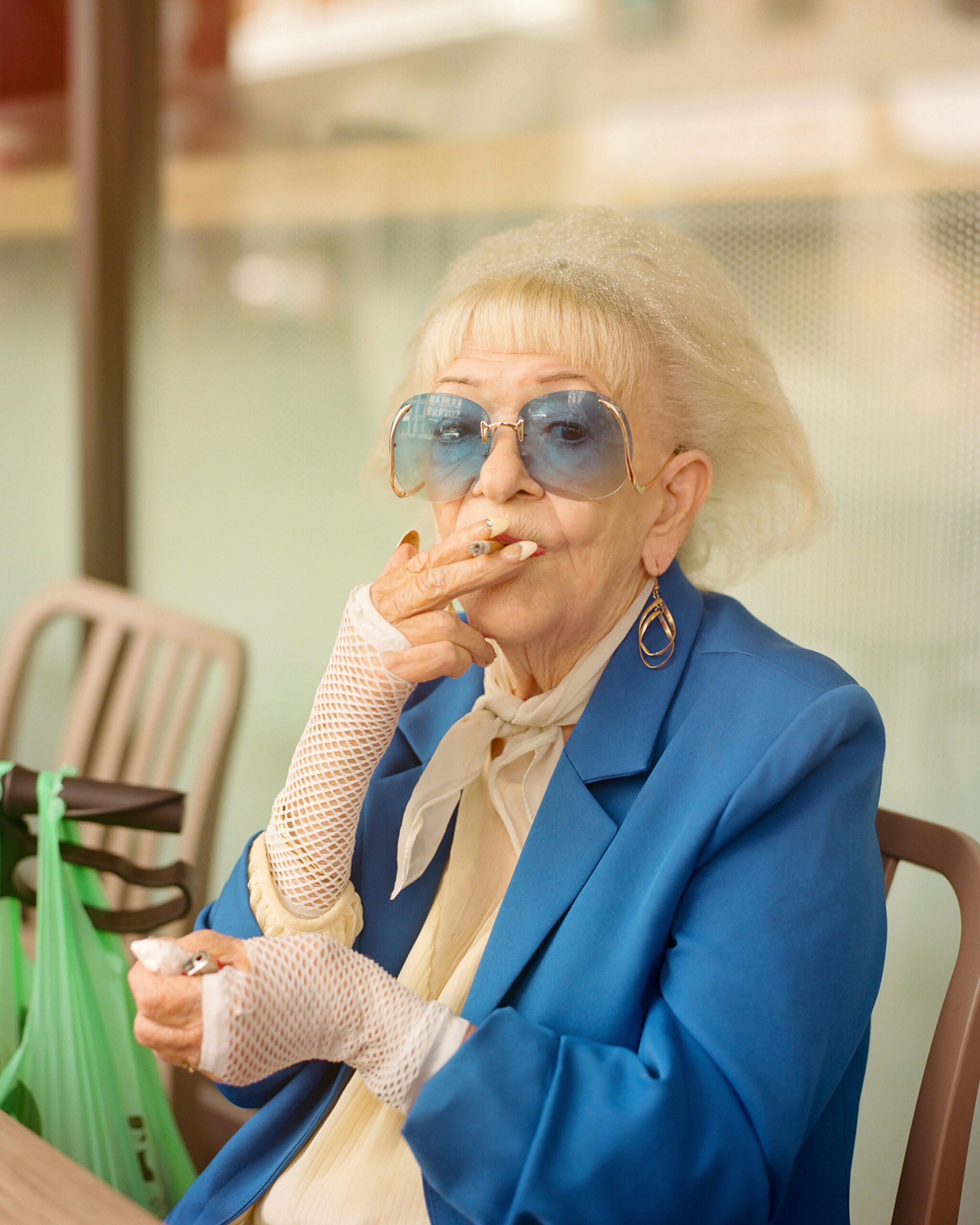 Eine alte Dame in blauem Blazer raucht eine Zigarette.