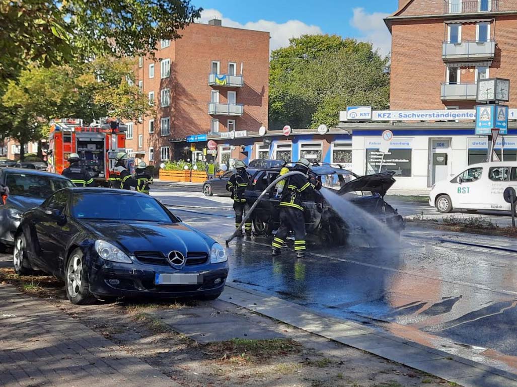 Feuerwehr löscht ein Auto auf einer Straße