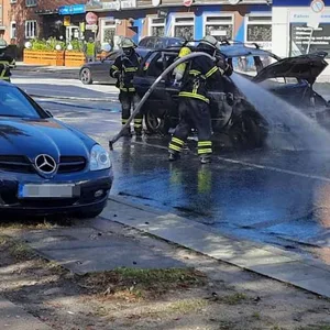 Feuerwehr löscht ein Auto auf einer Straße