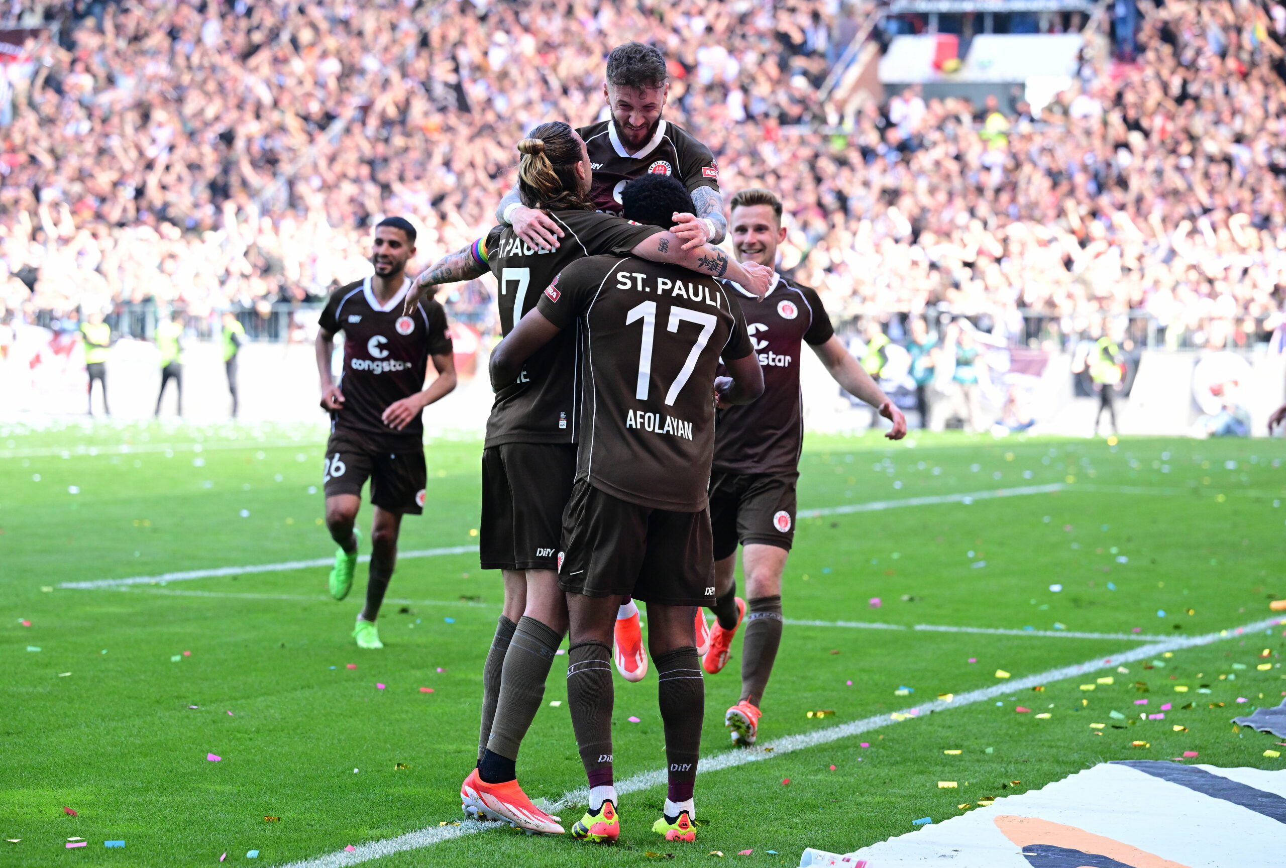 Jackson Irvine, Marcel Hartel und Oladapo Afolayan umarmen sich beim Jubeln