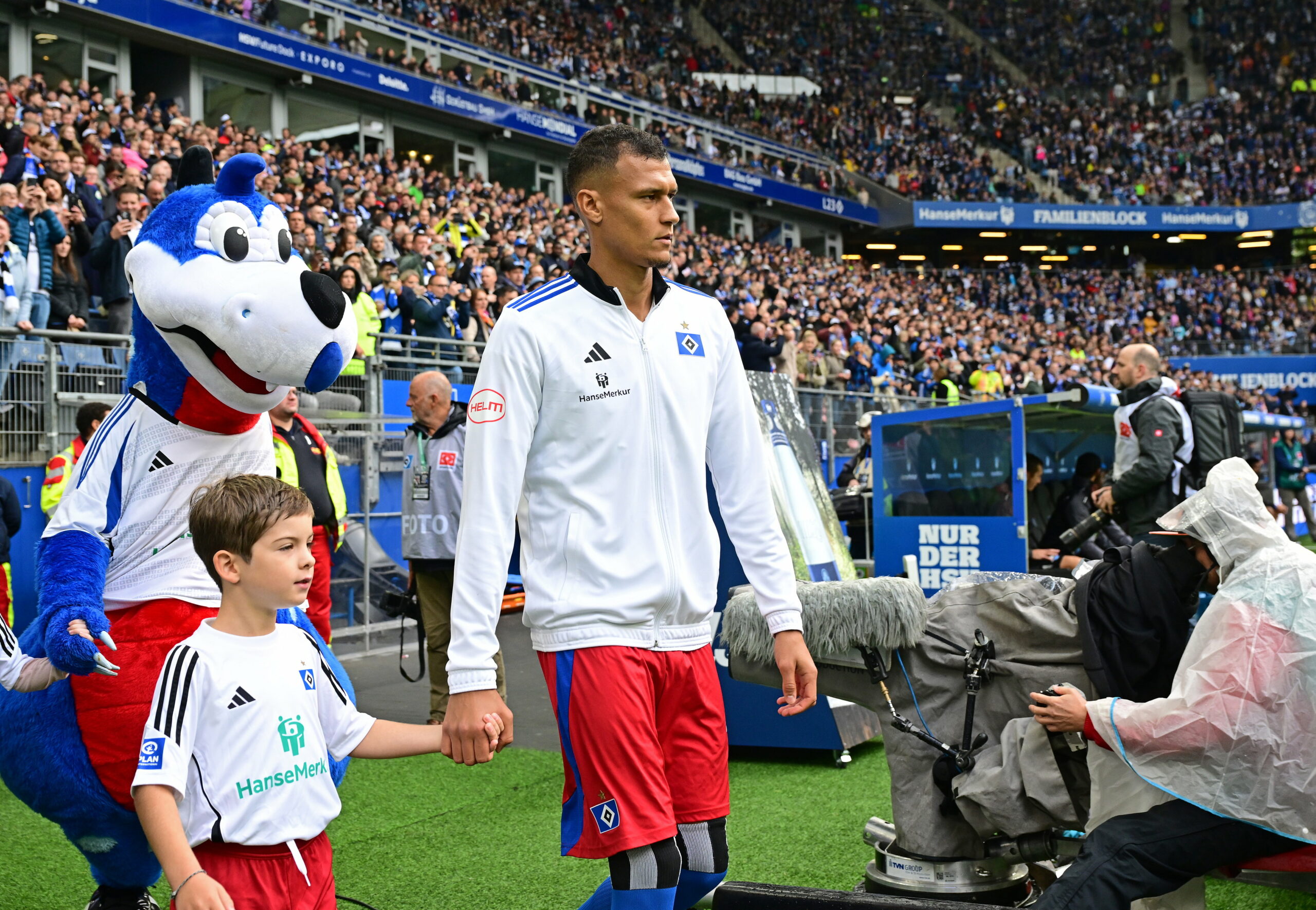 Davie Selke läuft mit einem kleinen Jungen an der Hand ins Volksparkstadion ein