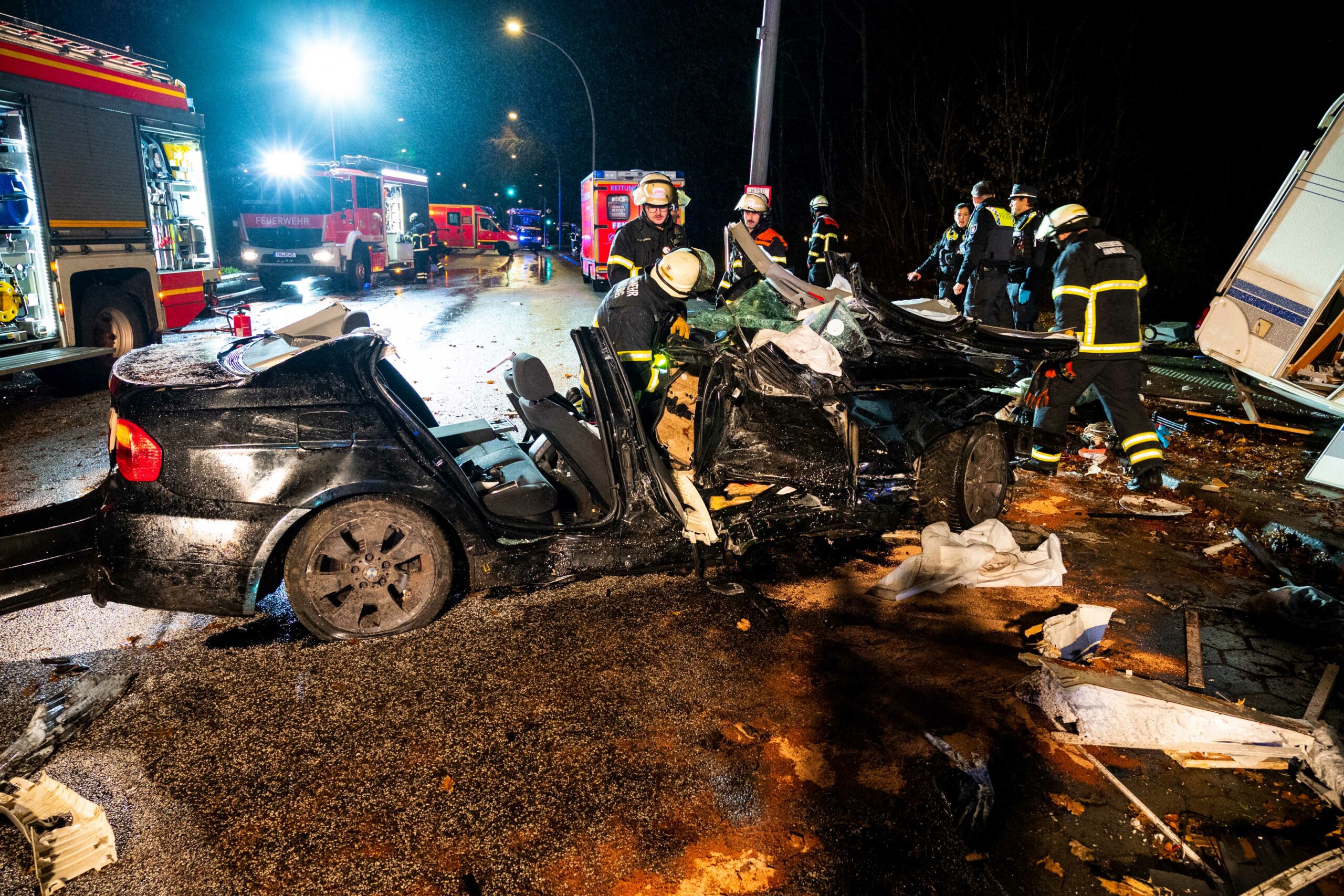 Der zerstörte BMW und rechts das Wohnwagenwrack nach dem Unfall auf dem Reinbeker Redder in Hamburg-Lohbrügge.