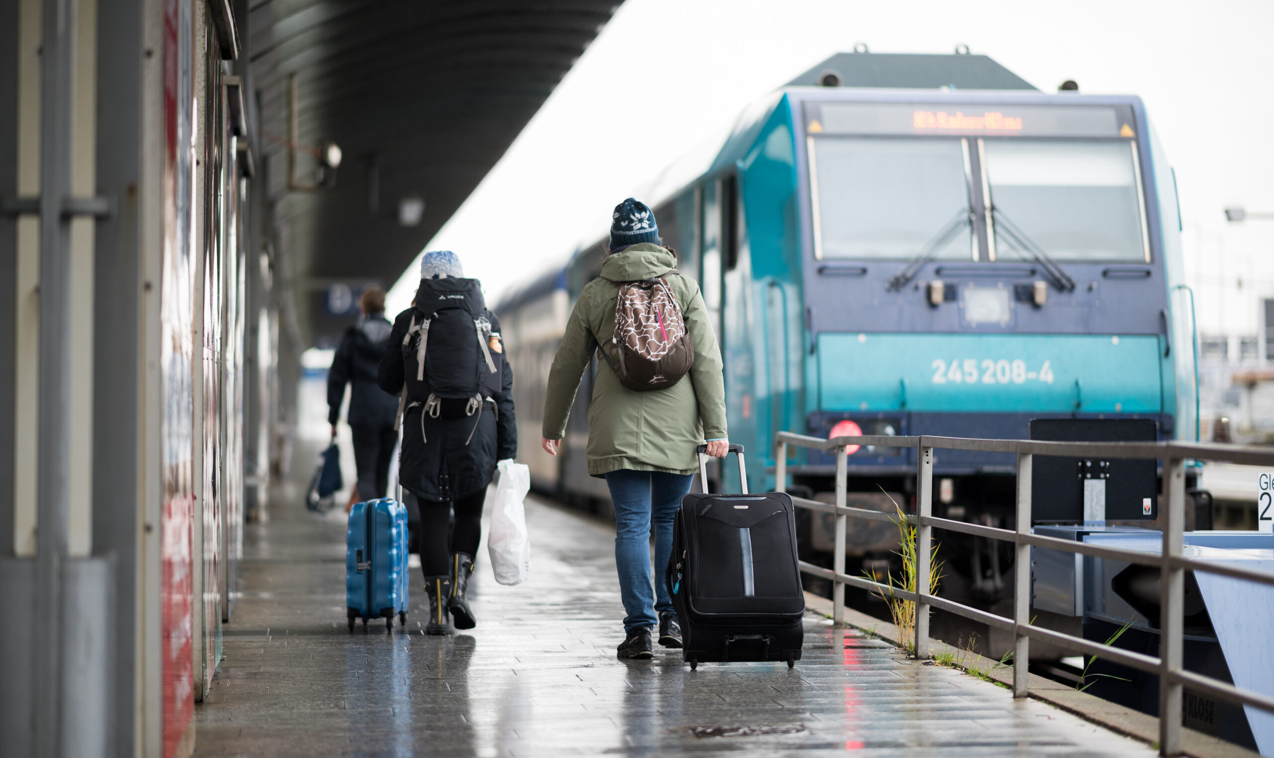 Reisende gehen im Bahnhof Westerland über einen Bahnsteig zu einem wartenden Zug.