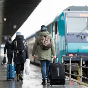 Reisende gehen im Bahnhof Westerland über einen Bahnsteig zu einem wartenden Zug.