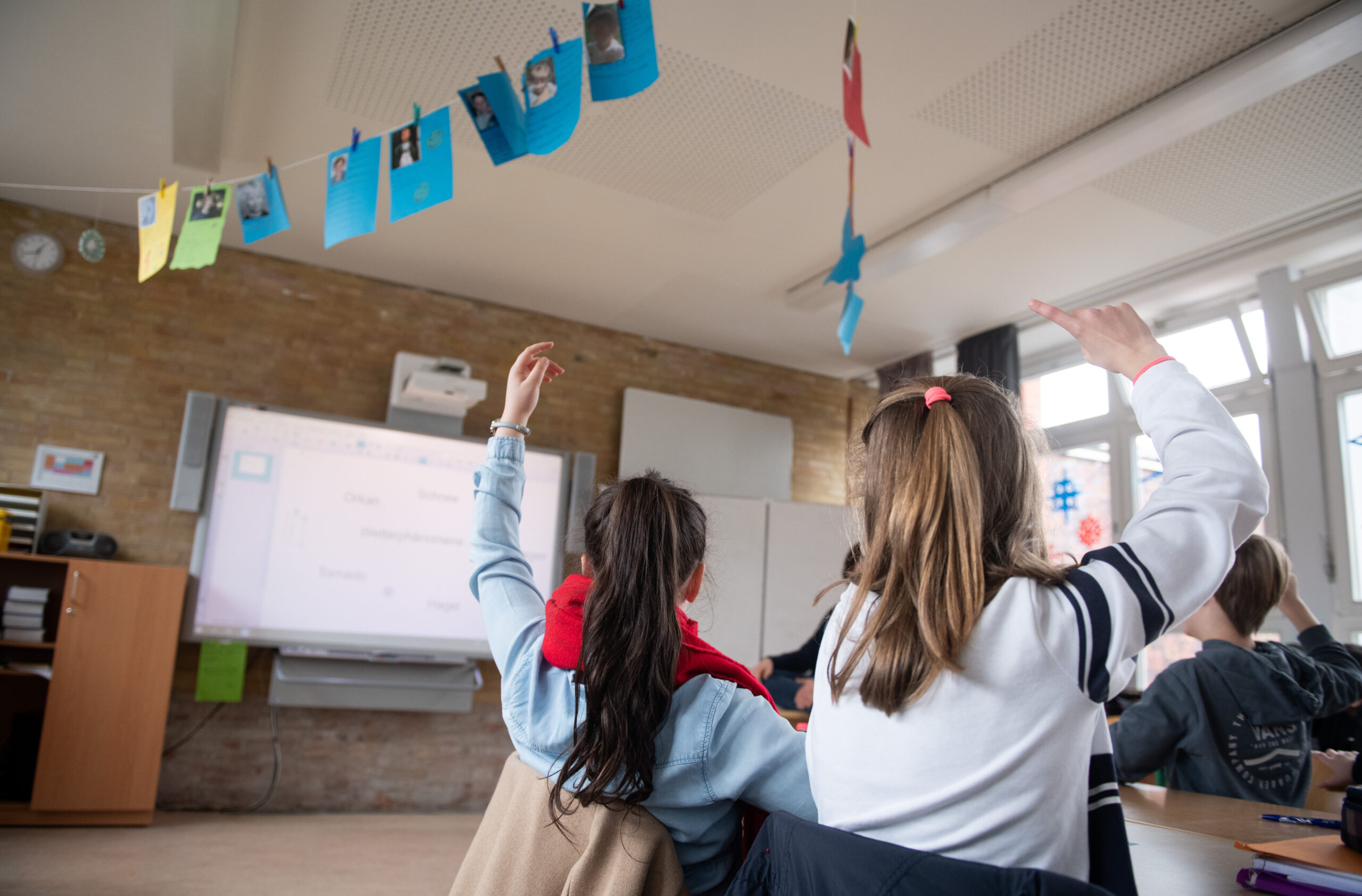 Schüler einer fünften Klasse eines Gymnasiums melden sich im Unterricht.