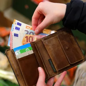 Eine Frau zählt Geldscheine in einem Supermarkt.