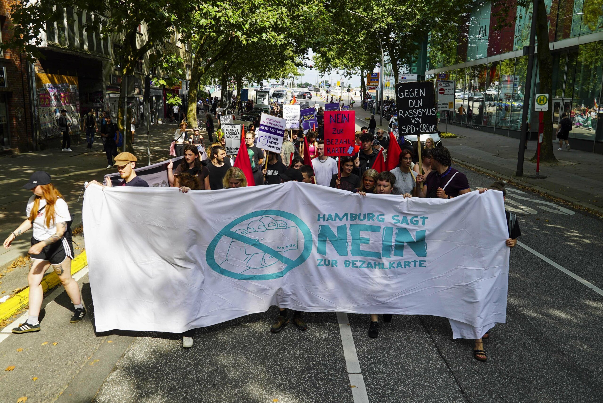 Protestierende mit einem Banner „Nein zur Bezahökarte“