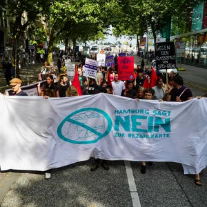 Protestierende mit einem Banner „Nein zur Bezahökarte“