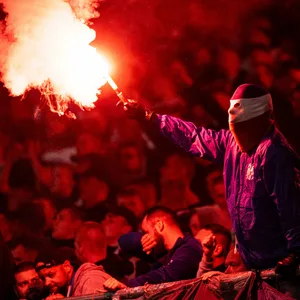 Ein maskierter Ultra von Hansa Rostock zündet Pyrotechnik im Fanblock