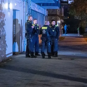 Polizisten stehen vor einem Mehrfamilienhaus im Berliner Stadtteil Marzahn.