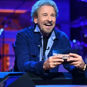 Ein älterer Mann mit Locken (Thomas Gottschalk) sitzt in einer Show