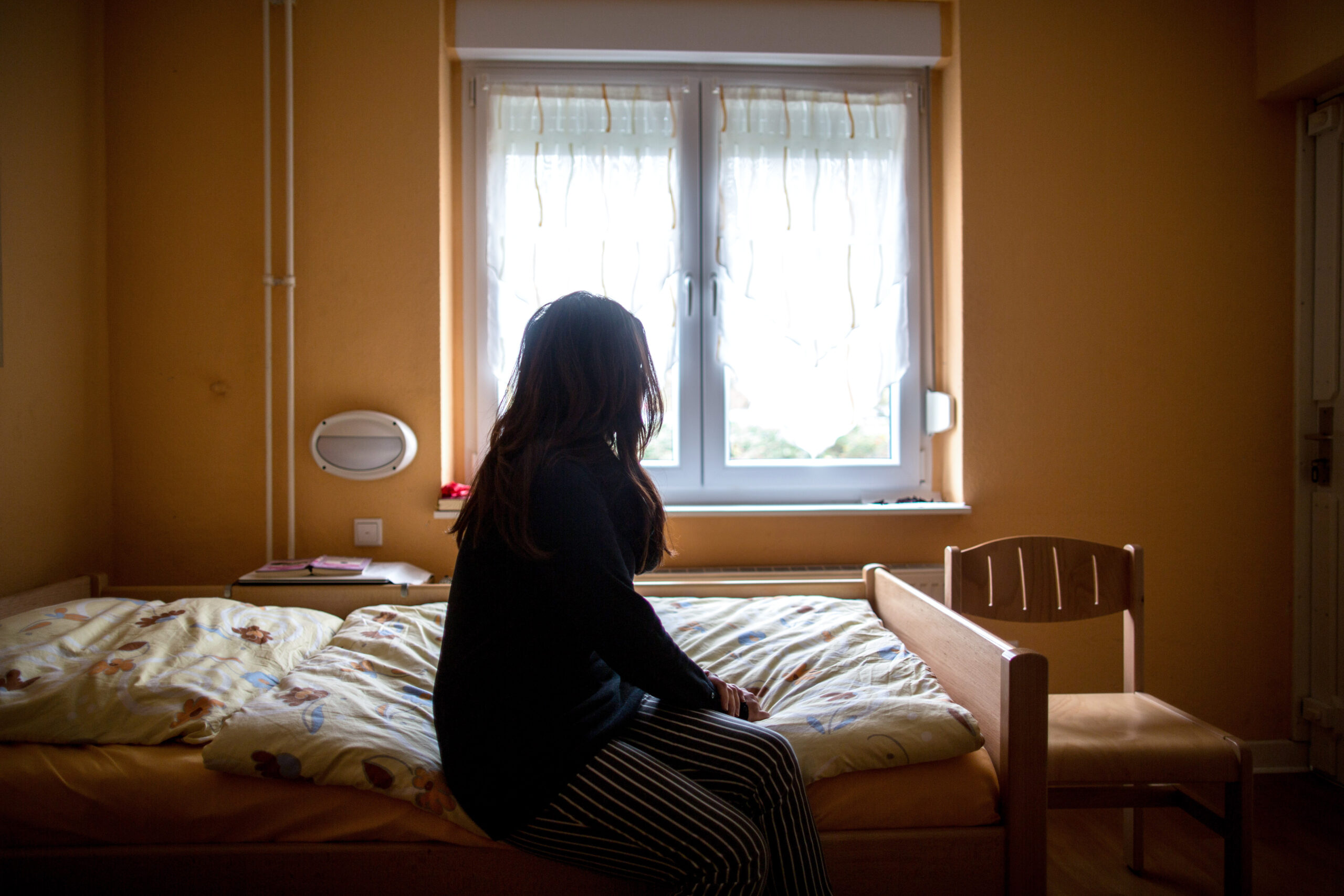 Eine Frau sitzt in einem Hamburger Frauenhaus auf dem Bett (Symbolfoto). Eine 28-jährige Türkin, die dort Schutz suchte, wurde abgeschoben.