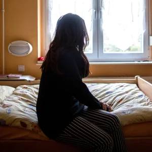 Eine Frau sitzt in einem Hamburger Frauenhaus auf dem Bett (Symbolfoto). Eine 28-jährige Türkin, die dort Schutz suchte, wurde abgeschoben.