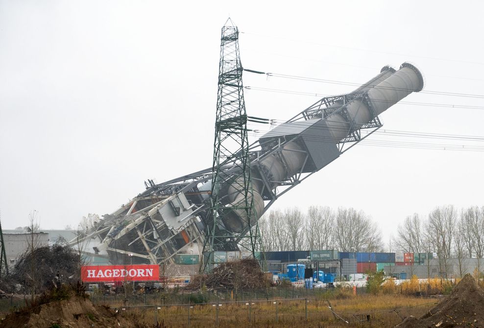 Der Doppel-Schornstein des stillgelegten Kohlekraftwerks Moorburg kippt nach seiner Sprengung um.