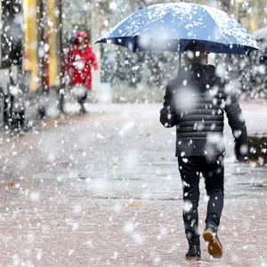 Ein Mann geht bei Schneefall durch die Fußgängerzone.