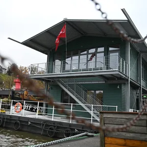 Das Besucherzentrum ist hinter einem Geländer zu sehen. Das neue Gebäude am Museumshafen Oevelgönne ist alten Hafenliegern nachempfunden und soll zukünftig als Besucher- und Informationszentrum über die historischen Schiffe und die Arbeit des Vereins informieren.