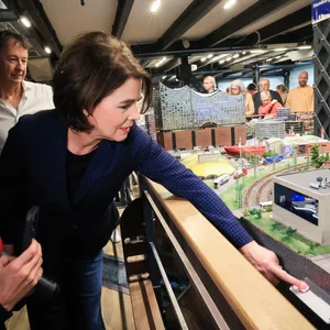 Eine Frau drückt auf einen Knopf einer Modelleisenbahn