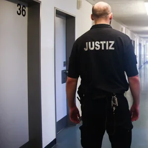 Ein Vollzugsbeamter geht in der JVA Billwerder in Hamburg einen Gang entlang.