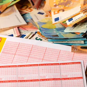 Zwei Lottoscheine und Geldscheine ausgelegt