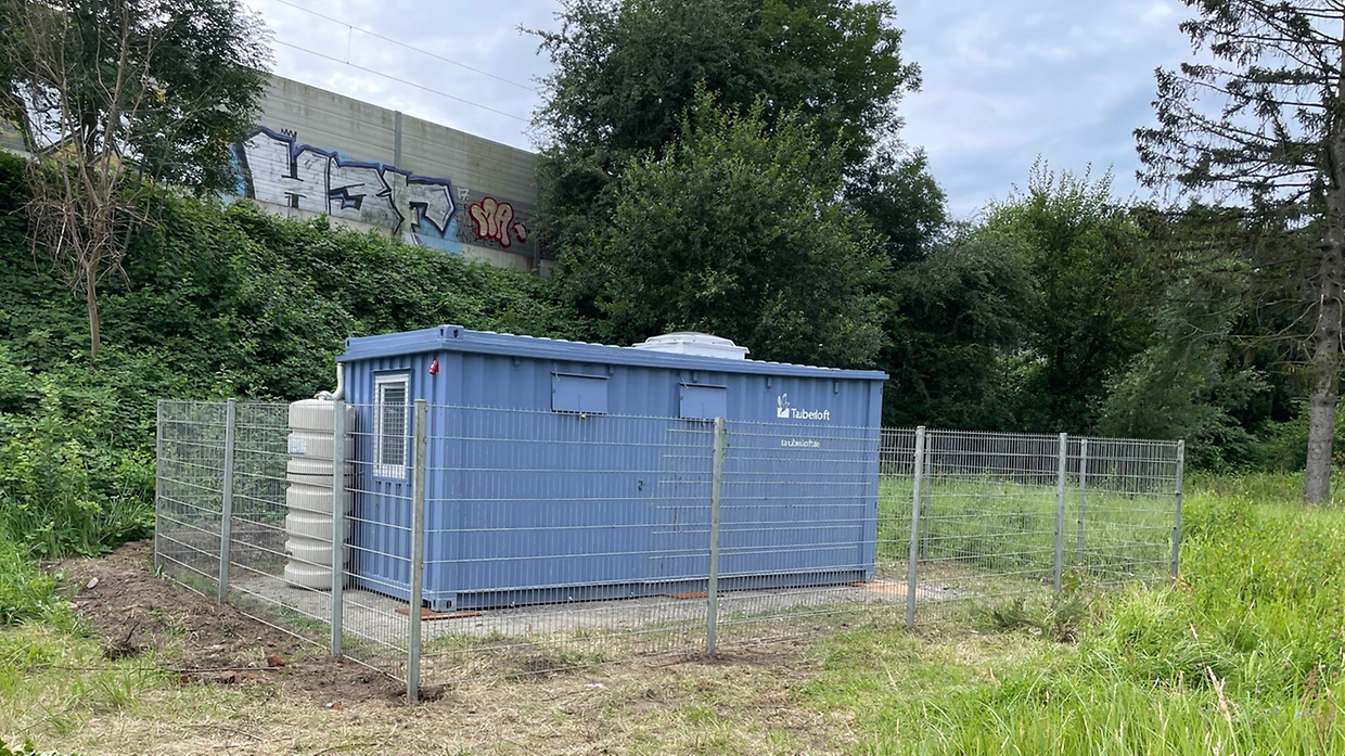 Ein blauer Container umringt von einem Zaun