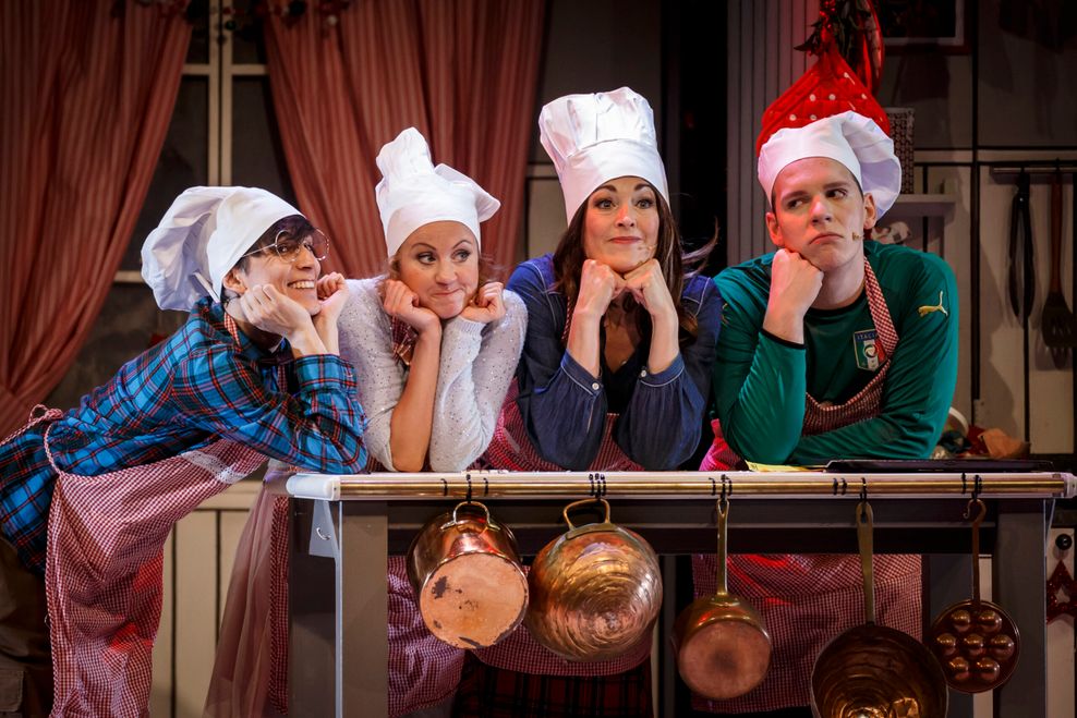 Das Ensemble von „Die Weihnachtsbäckerei“ mit Koch-Mützen in einer Küche.