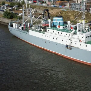 Ein graues Schiff liegt am Kai. Im Hintergrund ist eine Baustelle.