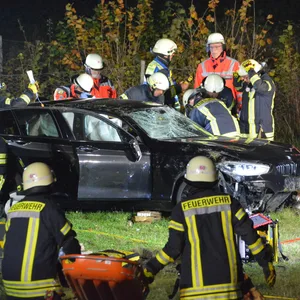 Feuerwehrleute stehen um das völlig zerstörte Fahrzeug