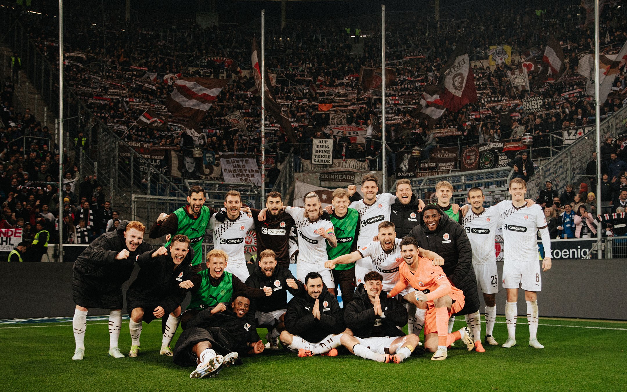 St. Paulis Spieler stehen für ein Foto vor der Fankurve