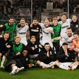 St. Paulis Spieler stehen für ein Foto vor der Fankurve