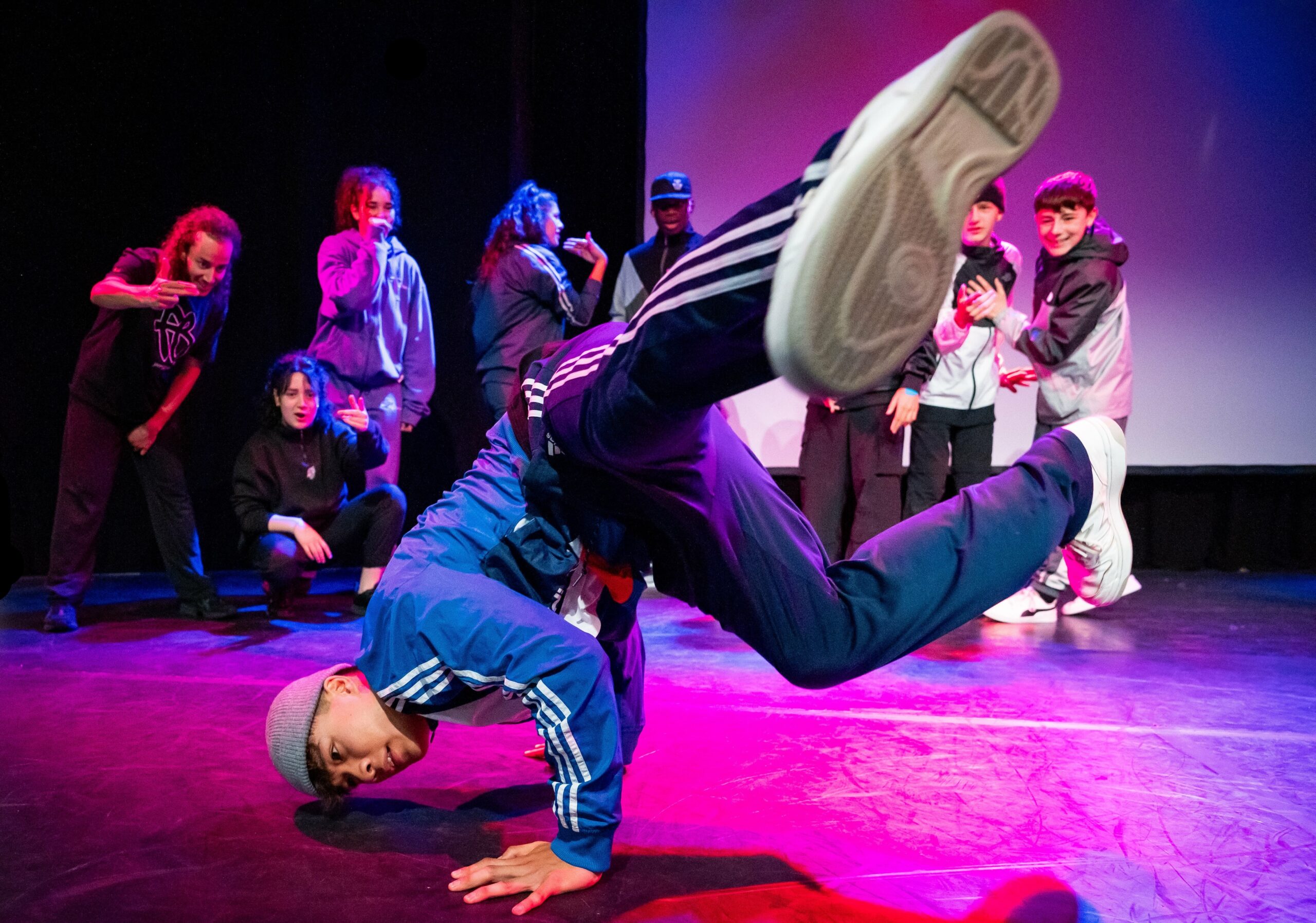 Ein Breakdancer, bei lila Licht am Performen auf Kampnagel