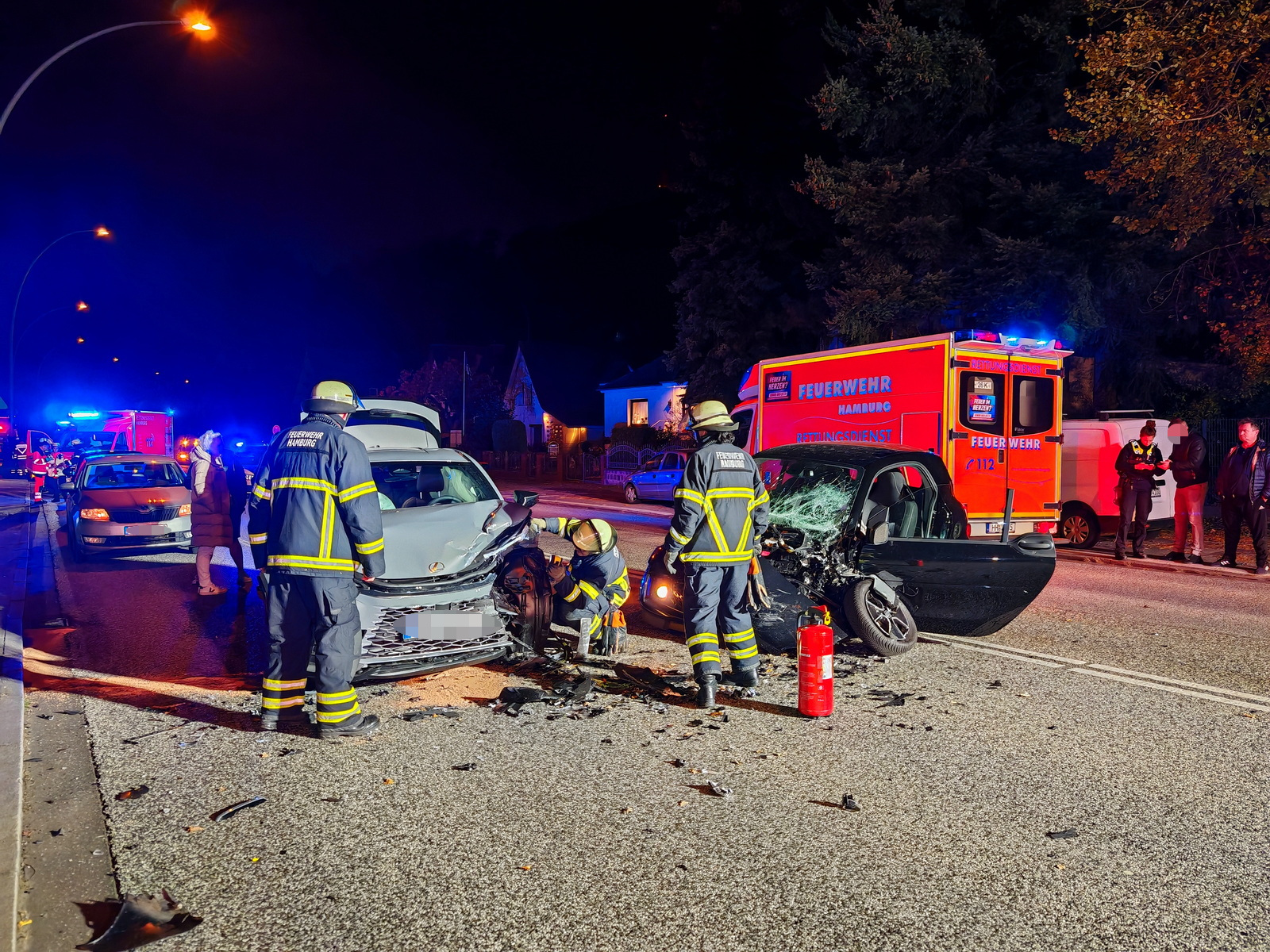 Zwei völlig zerstörte Autos stehen auf der Fahrbahn umgeben von Rettungskräften